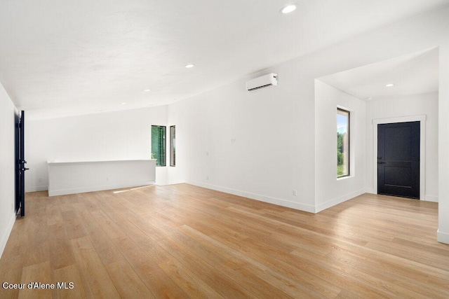 unfurnished living room featuring recessed lighting, baseboards, light wood-style flooring, and a wall mounted AC