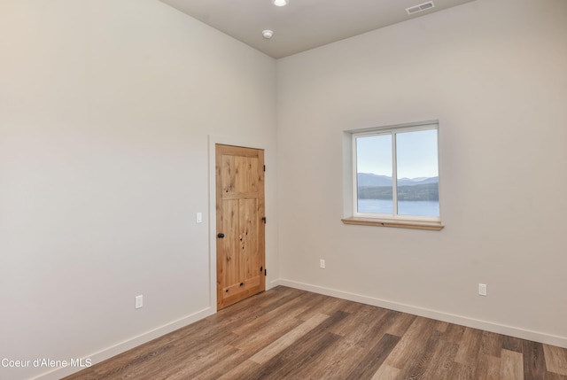 spare room with baseboards, wood finished floors, and visible vents