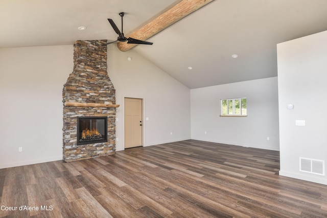 unfurnished living room featuring wood finished floors, a stone fireplace, ceiling fan, beamed ceiling, and visible vents