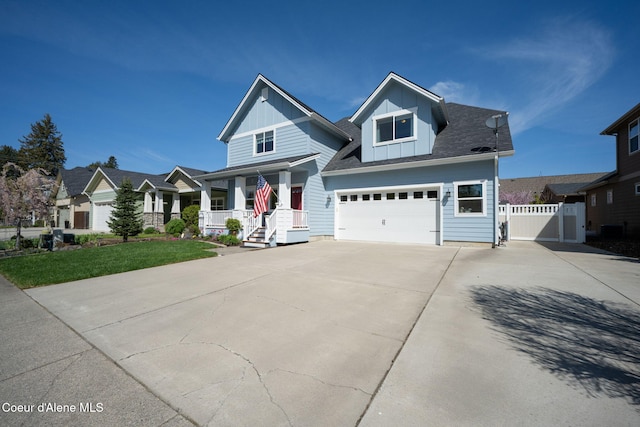 craftsman inspired home with a porch, board and batten siding, a garage, fence, and concrete driveway