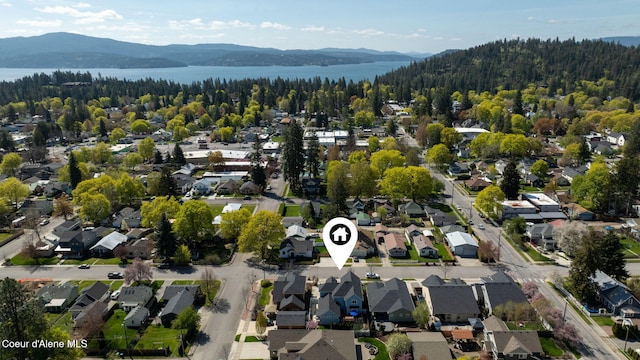 birds eye view of property with a water and mountain view, a view of trees, and a residential view