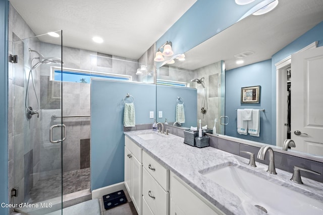 full bath with a sink, a stall shower, and double vanity