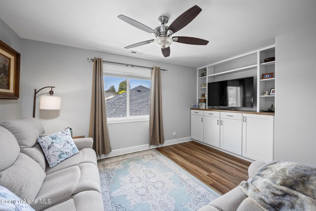 living area with visible vents, baseboards, ceiling fan, and wood finished floors