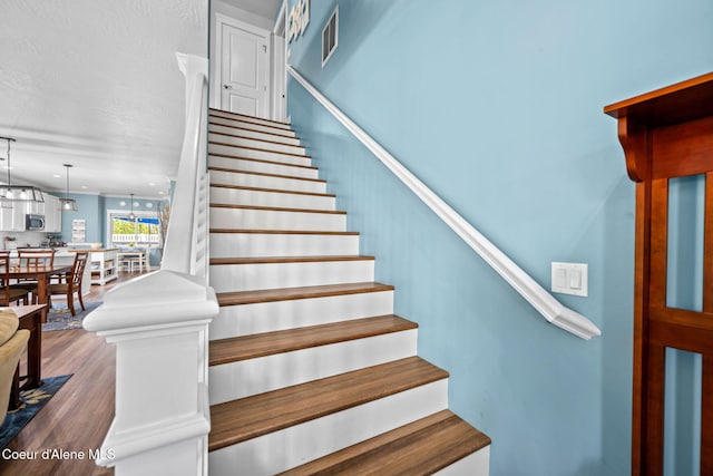 stairs with wood finished floors and visible vents