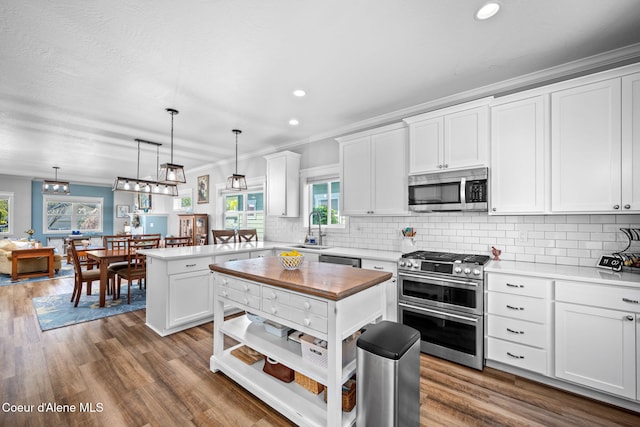 kitchen with white cabinets, a sink, stainless steel appliances, a peninsula, and decorative backsplash