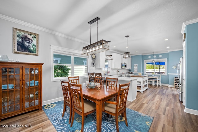 dining room featuring recessed lighting, baseboards, ornamental molding, and light wood-style flooring