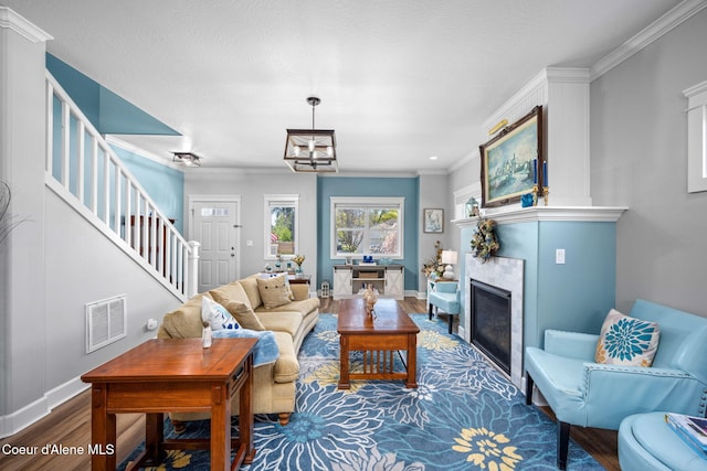 living area featuring visible vents, crown molding, wood finished floors, stairway, and a glass covered fireplace