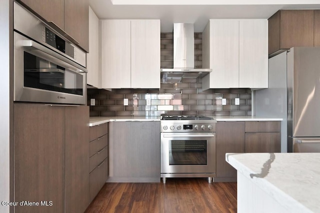 1579 W Riverstone Dr # 306, Coeur Dalene, ID 83814 - kitchen featuring modern cabinets, tasteful backsplash, appliances with stainless steel finishes, and wall chimney range hood