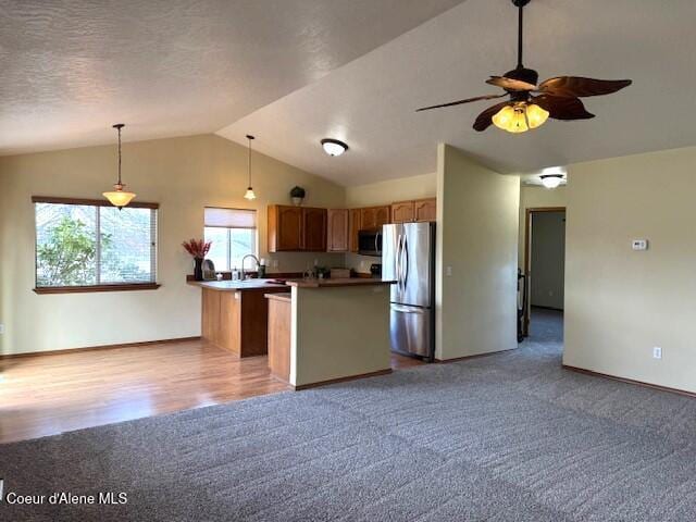 2359 N Alfalfa Loop, Post Falls, ID 83854 - kitchen featuring vaulted ceiling, hanging light fixtures, light carpet, stainless steel appliances, and baseboards