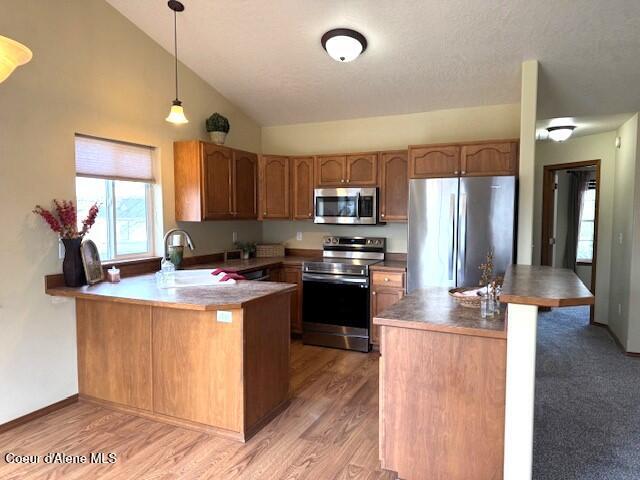 2359 N Alfalfa Loop, Post Falls, ID 83854 - kitchen featuring a sink, light wood-style floors, pendant lighting, stainless steel appliances, and a peninsula