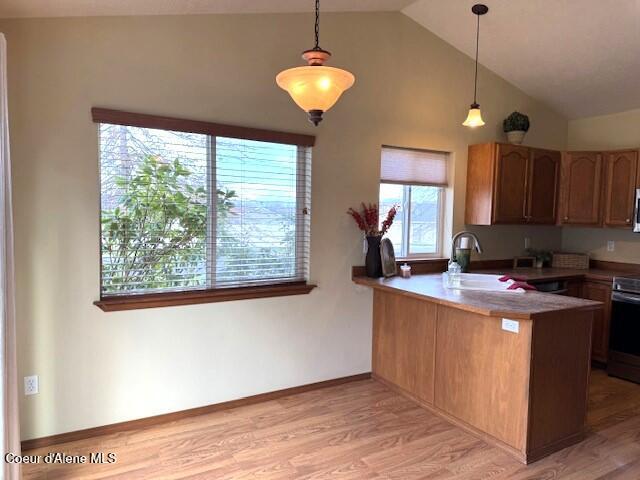 2359 N Alfalfa Loop, Post Falls, ID 83854 - kitchen featuring lofted ceiling, a peninsula, light wood-style flooring, and a wealth of natural light