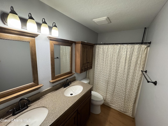 110 W 15th Ave, Post Falls, ID 83854 - bathroom with toilet, double vanity, wood finished floors, a textured ceiling, and a shower with shower curtain