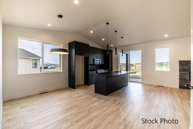 11506 N Clapton Ln, Rathdrum, ID 83858 - kitchen with appliances with stainless steel finishes, dark countertops, a kitchen island with sink, dark cabinetry, and baseboards