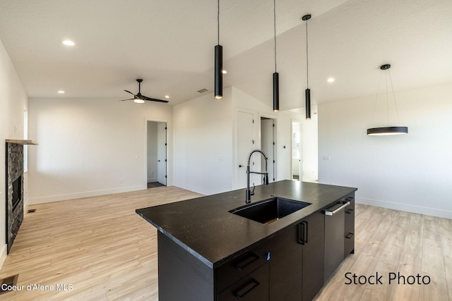 11506 N Clapton Ln, Rathdrum, ID 83858 - kitchen with a sink, a ceiling fan, a kitchen island with sink, light wood-style flooring, and baseboards