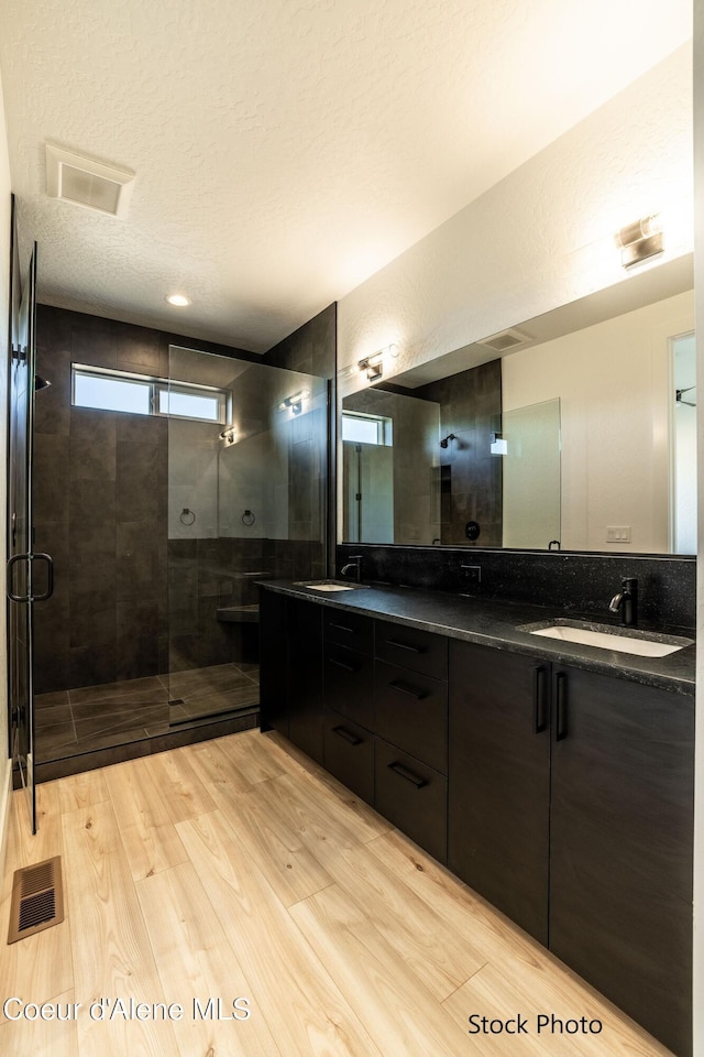 11506 N Clapton Ln, Rathdrum, ID 83858 - bathroom featuring a shower stall, double vanity, wood finished floors, and a textured ceiling
