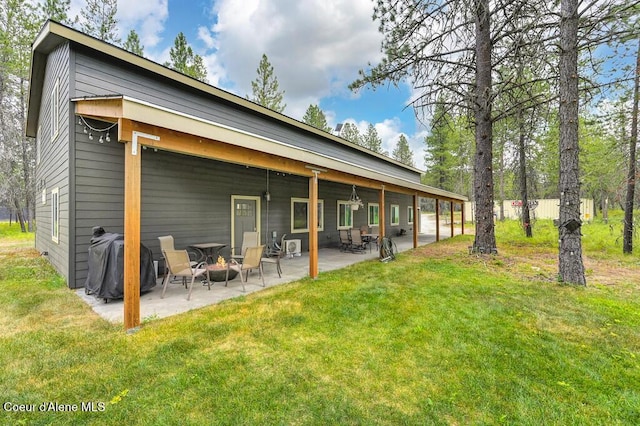 rear view of house with a patio area, an outdoor fire pit, and a yard