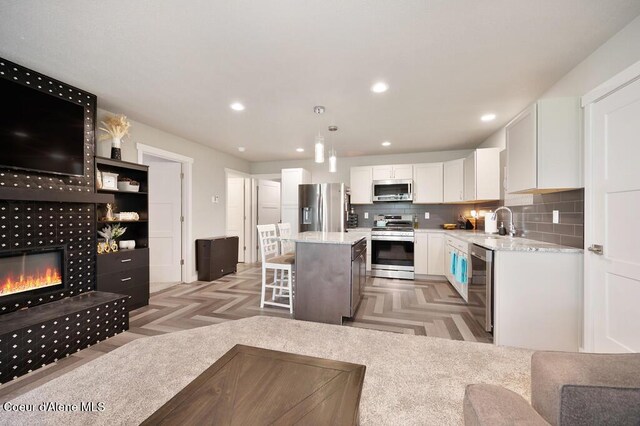 kitchen with a fireplace, white cabinetry, a breakfast bar area, appliances with stainless steel finishes, and a sink
