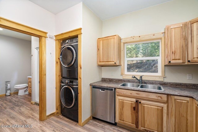 laundry room featuring stacked washer / drying machine, a sink, laundry area, and light wood finished floors