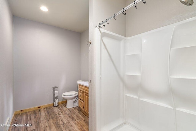 bathroom with toilet, baseboards, walk in shower, wood finished floors, and vanity