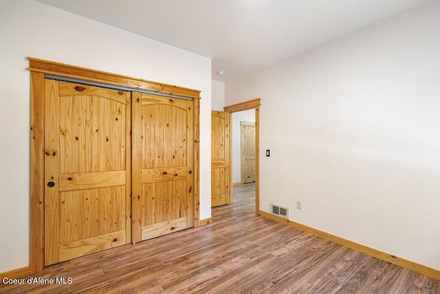 unfurnished bedroom with wood finished floors, visible vents, and baseboards