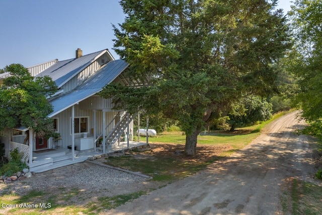 view of front facade featuring board and batten siding, a chimney, stairway, and metal roof