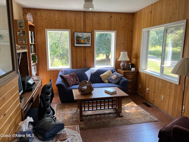 living room with wooden walls, wood finished floors, and visible vents