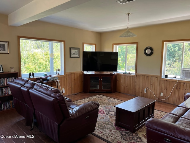 living room featuring wainscoting, wood walls, wood finished floors, and visible vents