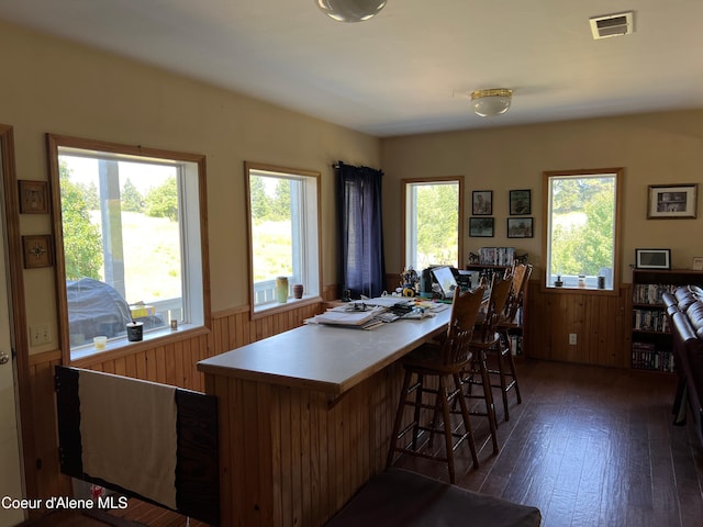 dining room featuring wood finished floors, visible vents, a wainscoted wall, and a healthy amount of sunlight