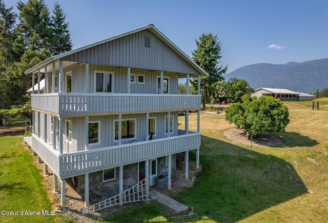back of property featuring cooling unit, a yard, and a mountain view