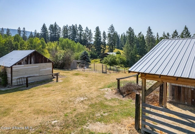 view of yard featuring an exterior structure, a view of trees, and an outbuilding