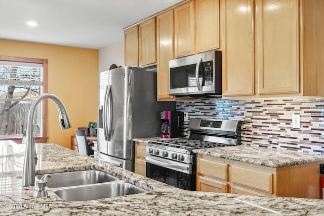 kitchen with appliances with stainless steel finishes, light brown cabinets, a sink, and decorative backsplash