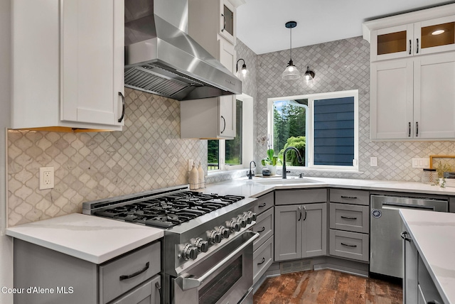 3825 E English Point Rd, Hayden, ID 83835 - kitchen with wall chimney exhaust hood, appliances with stainless steel finishes, gray cabinets, backsplash, and glass insert cabinets