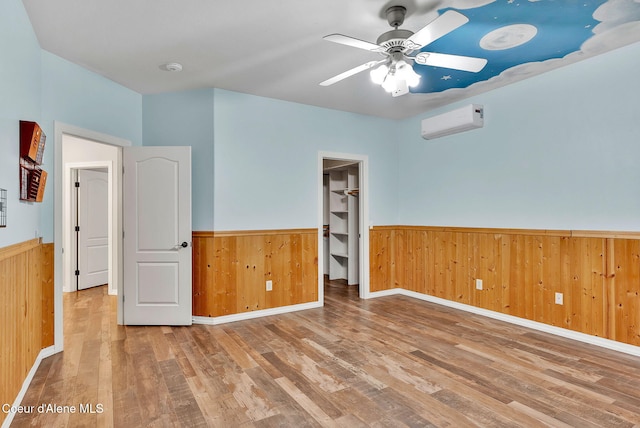 3825 E English Point Rd, Hayden, ID 83835 - unfurnished room with wainscoting, a wall unit AC, wood finished floors, wooden walls, and a ceiling fan