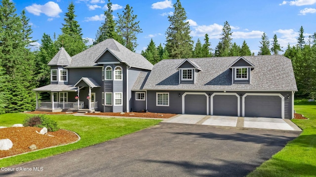 3825 E English Point Rd, Hayden, ID 83835 - view of front of house with covered porch, driveway, a front yard, a shingled roof, and a garage