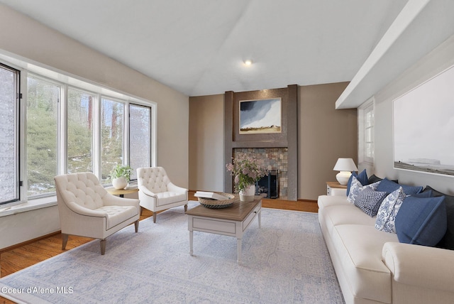 living area with a fireplace, lofted ceiling, a wealth of natural light, and wood finished floors