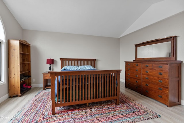 bedroom with vaulted ceiling, wood finished floors, and baseboards