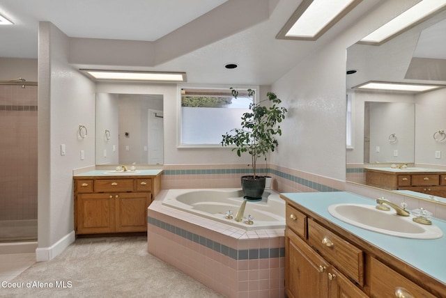 full bath featuring a shower stall, a bath, two vanities, and a sink