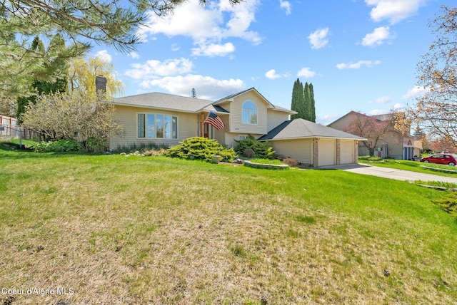 tri-level home featuring an attached garage, a front lawn, a chimney, and concrete driveway