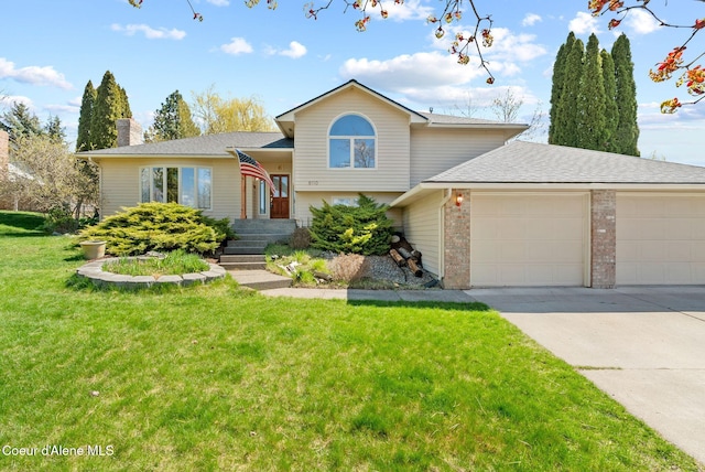split level home with concrete driveway, a front lawn, a chimney, and a garage