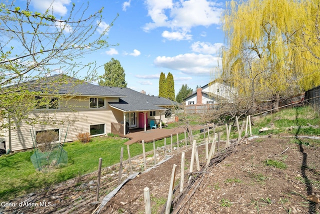back of property featuring a garden, fence, and a lawn