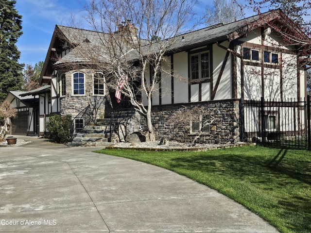 11268 N Friar Dr, Hayden, ID 83835 - tudor house with driveway, stone siding, a chimney, and fence