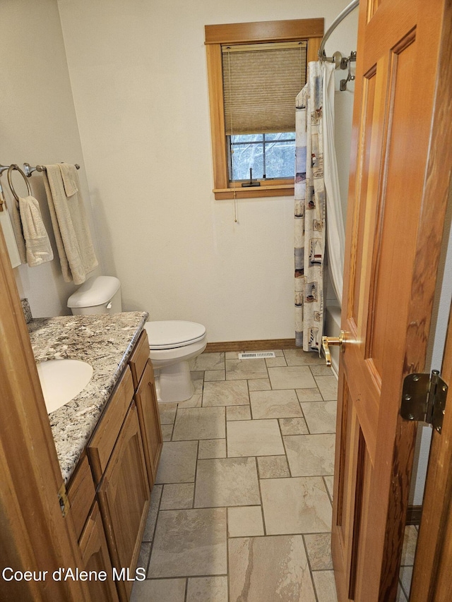 11268 N Friar Dr, Hayden, ID 83835 - full bathroom featuring toilet, stone tile floors, vanity, baseboards, and visible vents