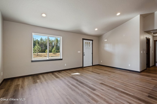 818 Sawbuck Rd, Spirit Lake, ID 83869 - unfurnished living room featuring wood finished floors, baseboards, vaulted ceiling, and recessed lighting