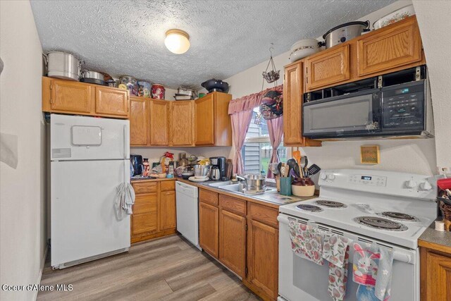 1515 E Elm Ave, Coeur Dalene, ID 83814 - kitchen with white appliances, a textured ceiling, light wood-style floors, light countertops, and a sink