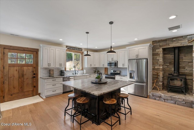 329 N Healing Dr, Blanchard, ID 83804 - kitchen with stainless steel appliances, plenty of natural light, a breakfast bar area, and a wood stove