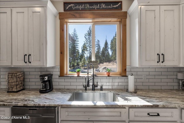 329 N Healing Dr, Blanchard, ID 83804 - kitchen with stainless steel dishwasher, backsplash, a sink, and white cabinetry