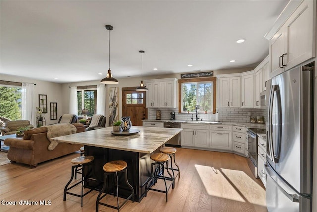329 N Healing Dr, Blanchard, ID 83804 - kitchen with a sink, open floor plan, backsplash, a kitchen bar, and appliances with stainless steel finishes