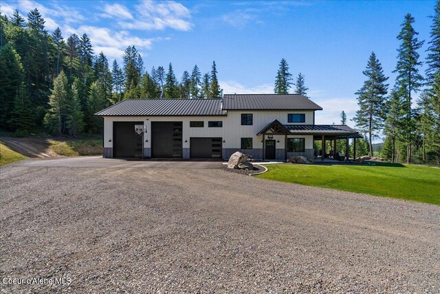 329 N Healing Dr, Blanchard, ID 83804 - modern farmhouse style home with dirt driveway, a front yard, metal roof, an attached garage, and board and batten siding