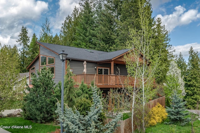 back of house with fence, a wooden deck, and roof with shingles