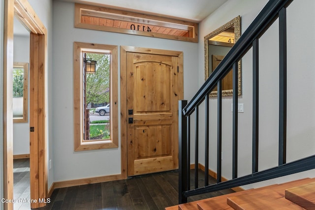 foyer entrance featuring baseboards, dark wood-style floors, and stairway